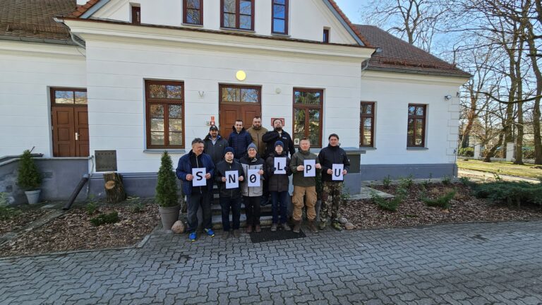 Członkowie PGK przed budynkiem MDK w Puławach trzymają kartki z literami SN0LPU